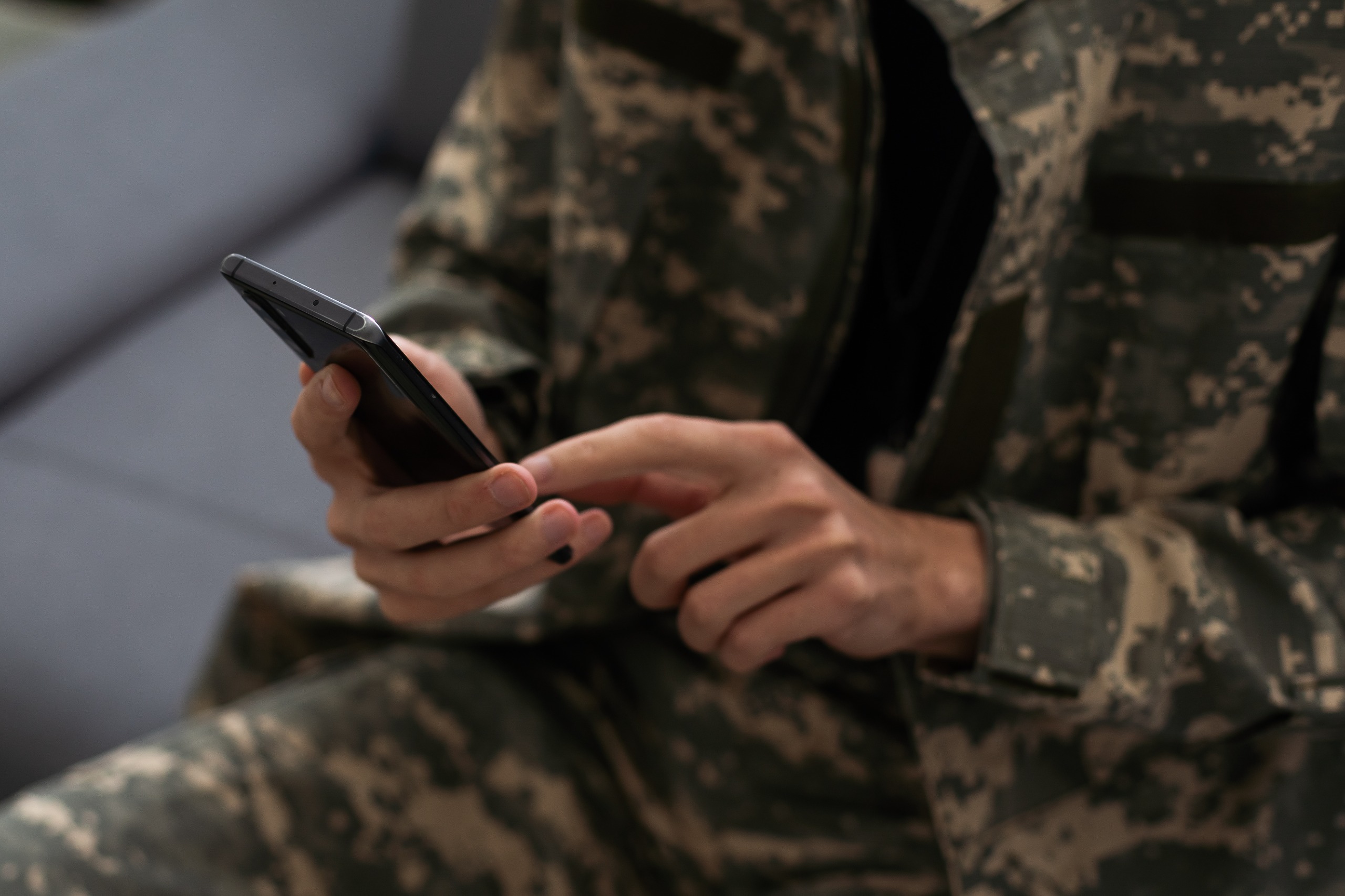 Person in military outfit texting on a mobile device